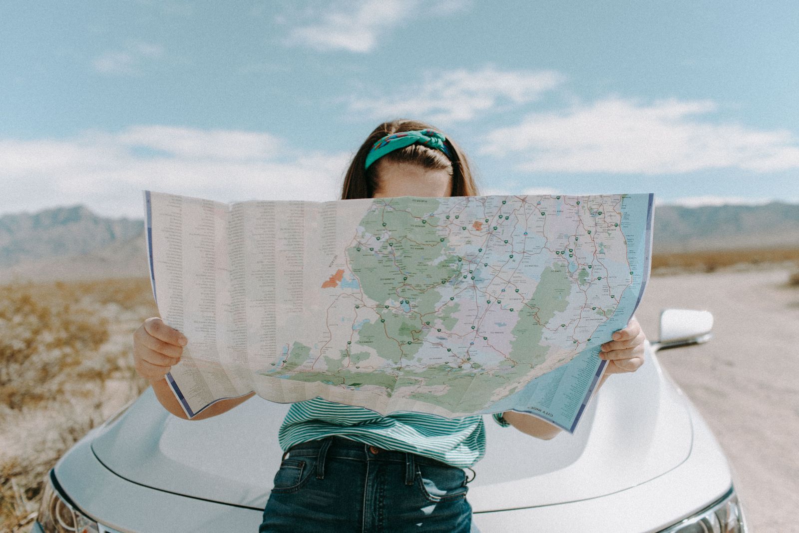 Traveller reading a road map beside a car